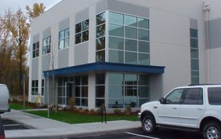 A side shot of a large, white building with a blue awning.