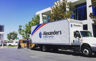 An Alexander's Mobility truck being loaded outside a commercial building.