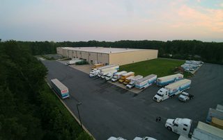 An aerial view of a large distribution center with cars parked outside.