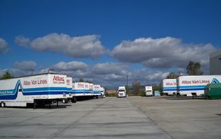A parking lot with several Atlas Van Lines semi trucks parked inside.